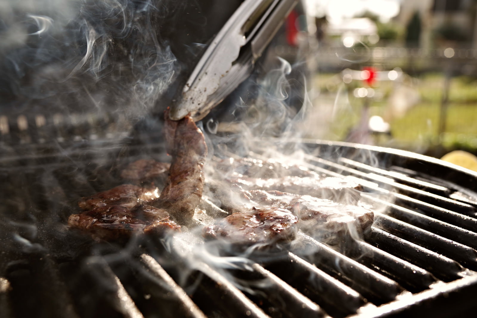 BBQグリルで炭火を使ってお肉を焼いている様子、煙が立ち上っている