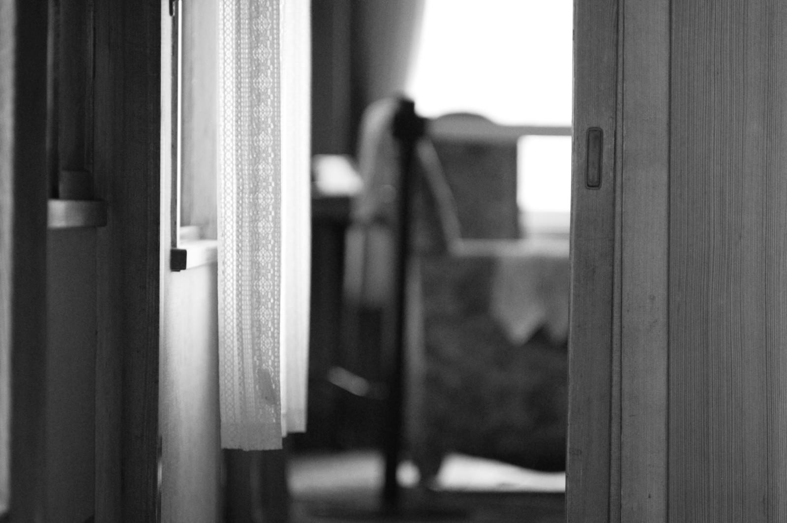 Monochrome room with a chair, visible through an open door