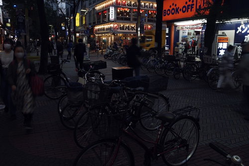 日が暮れた伊勢佐木商店街の夜景、街灯に照らされた駐輪場と開店した店舗の明かり