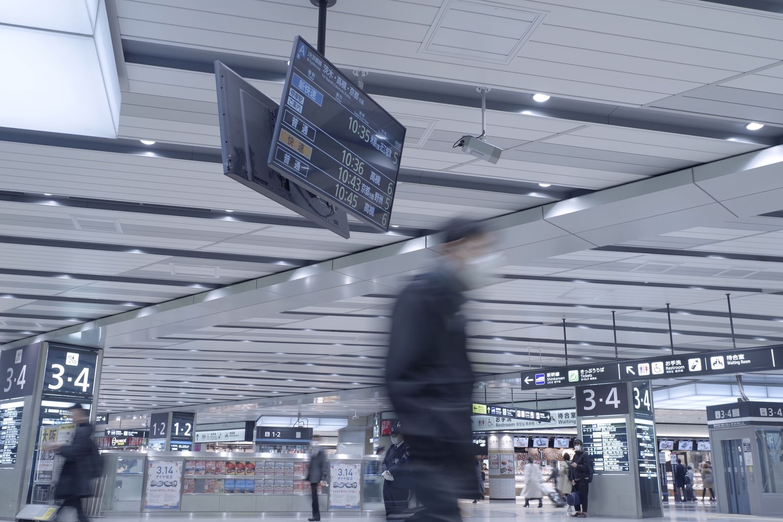 新大阪駅の駅構内で案内表示板の下を歩く人々