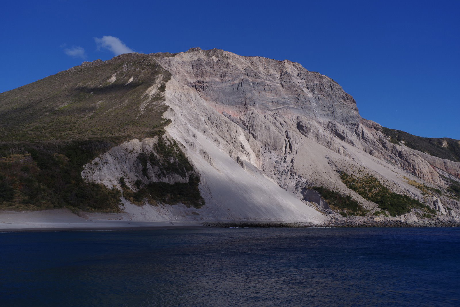 神津島の多幸湾から見た斜面崩落の山と青い海の風景