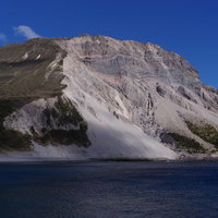 神津島の多幸湾から見える斜面が崩れた山と青い海の写真