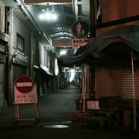 静まり返った夜のアーケード商店街の路地に置かれた通行止め看板の写真