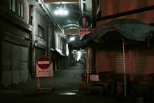 静まり返った夜のアーケード商店街の路地に置かれた通行止め看板