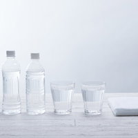 白いテーブルに並ぶペットボトル2本とグラスの水の写真