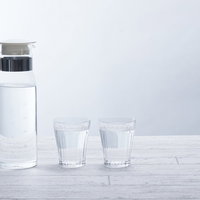 白いテーブルに置かれたポットとガラスタンブラーで水分補給の写真