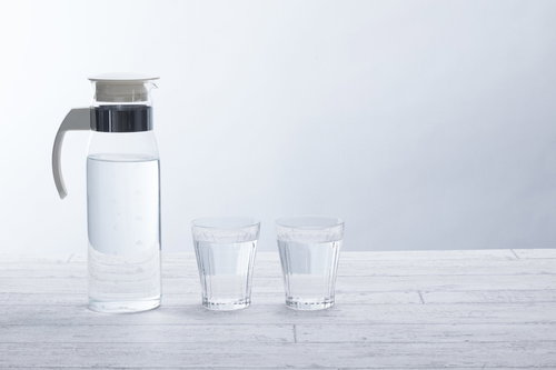 白いテーブルに置かれたポットとガラスタンブラーで水分補給
