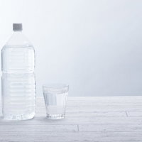 清潔感のある白い背景に置いた2リットルペットボトルとグラスの写真