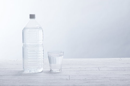清潔感のある白い背景に置いた2リットルペットボトルとグラス