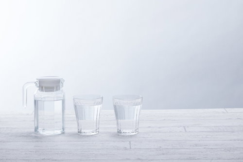 白いテーブル上に並ぶグラスとウォーターピッチャー