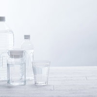 白い背景に並べたペットボトルと飲料水のグラスの写真