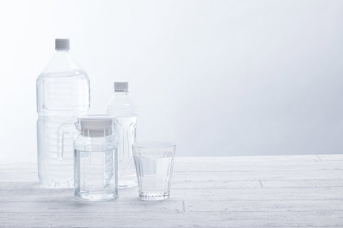 白い背景に並べたペットボトルと飲料水のグラス