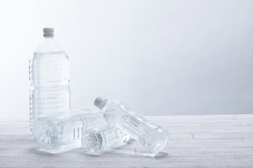 ペットボトルが次々と崩れる瞬間、複数本が連鎖して倒れる動的な構図