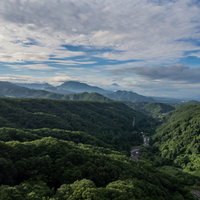 遠景に見る深緑の山々と山間を流れる渓谷の川の写真