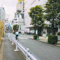 昼間の大久保公園前の通りの様子、自転車と街路樹のある都市風景の写真