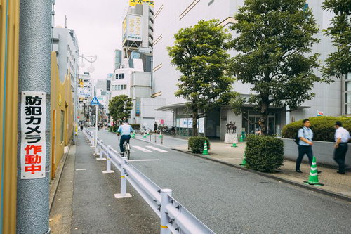 昼間の大久保公園前の通りの様子、自転車と街路樹のある都市風景