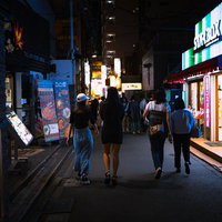 新大久保の路地裏を夜間に歩く人々の行き来の写真