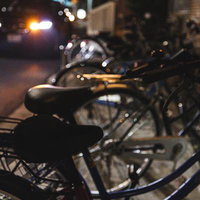 夜間のマンション駐輪場と通る自動車の細い路地の写真