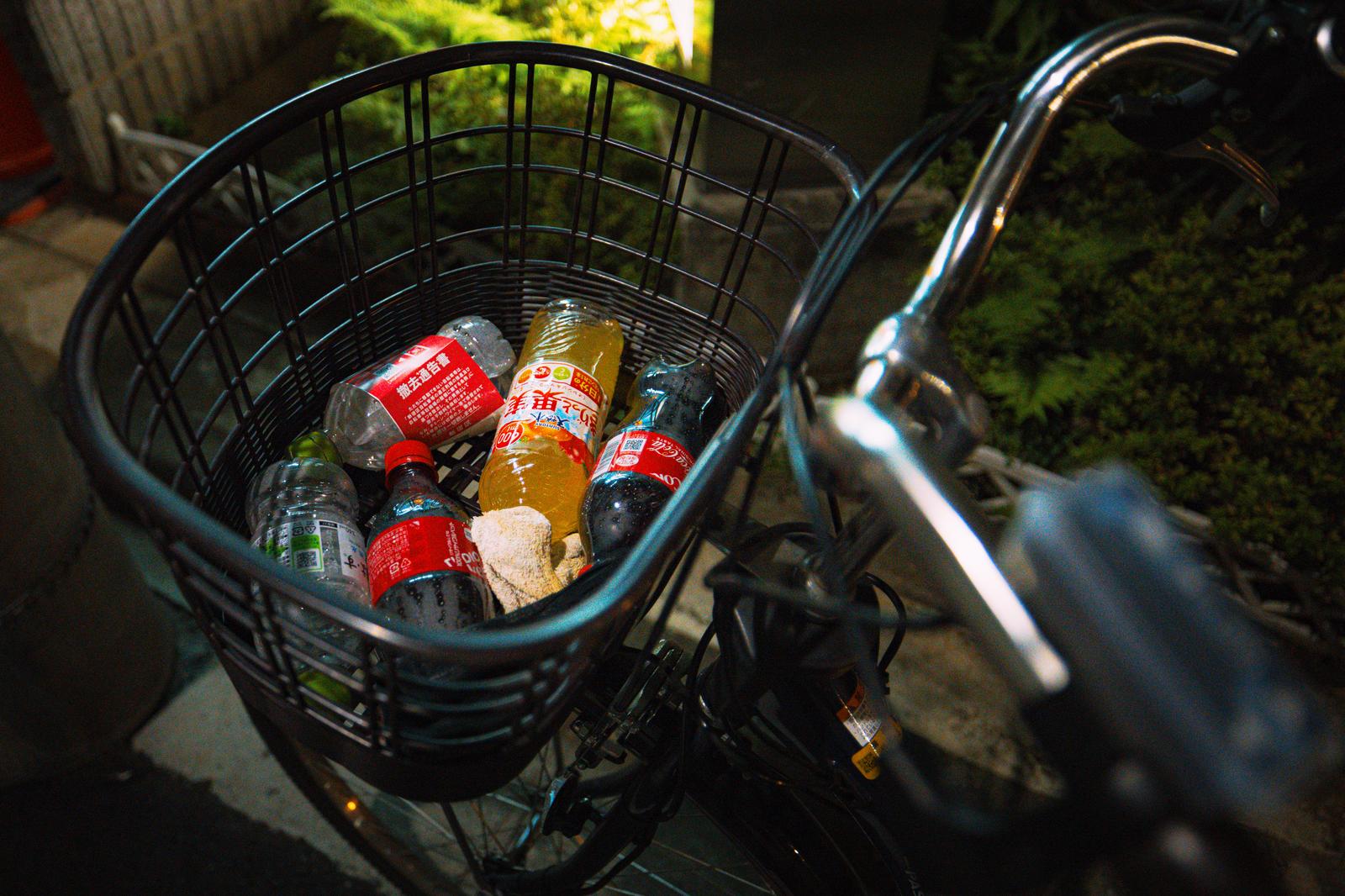 自転車のかごに投げ込まれた複数のペットボトルと缶類