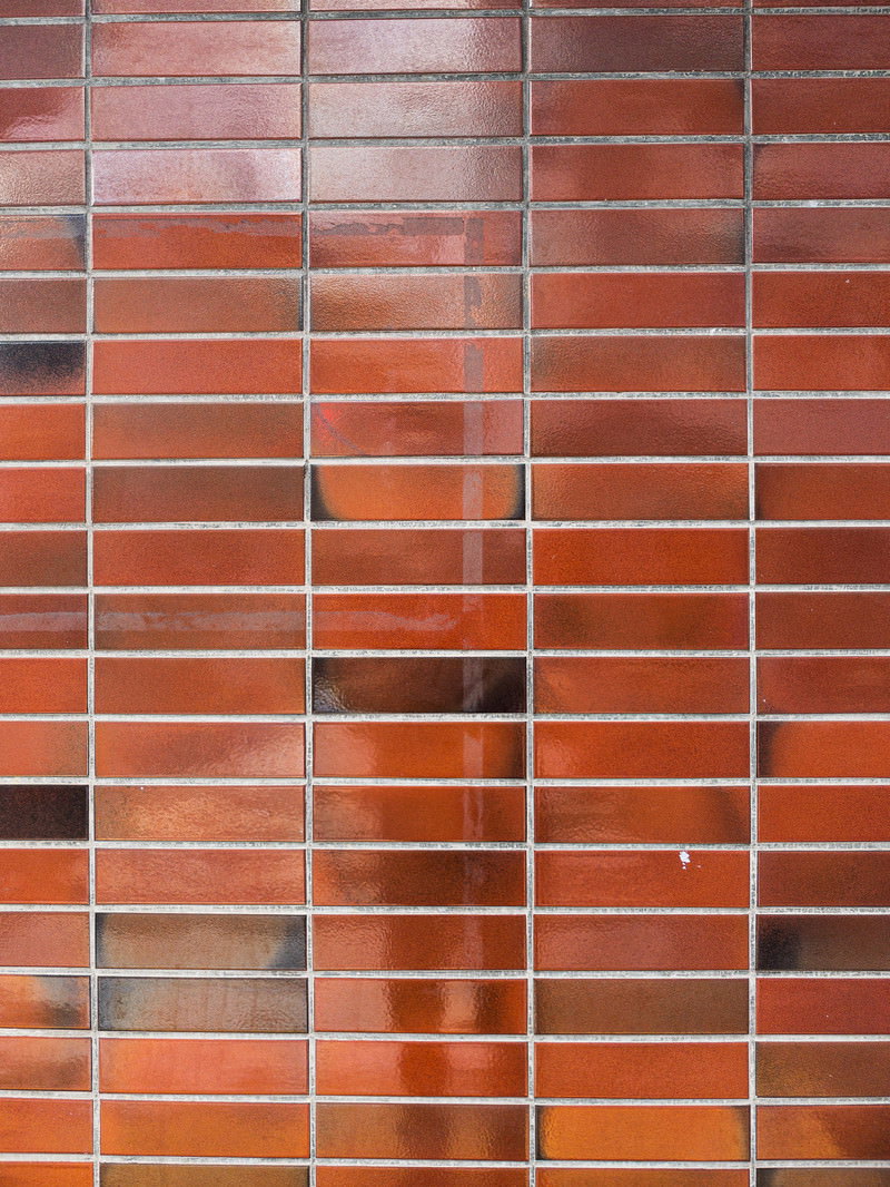 赤褐色のタイル壁にテープ跡が残るテクスチャーの写真