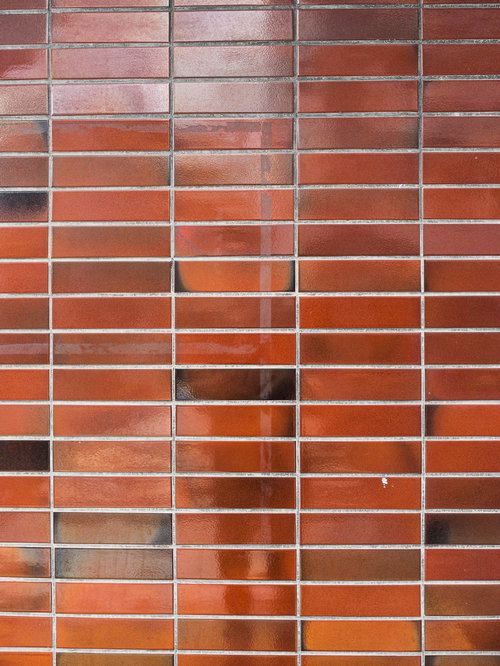 赤褐色のタイル壁に残るテープ跡のテクスチャー