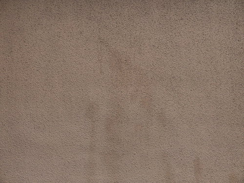 茶色いシミが残るグレーのモルタル仕上げ外壁