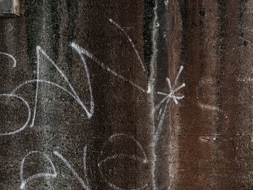 白いペイントが描かれた茶色いコンクリート外壁の落書き