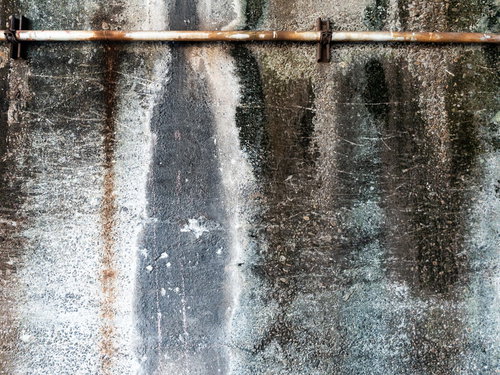 錆び付く丸パイプとコンクリート外壁の経年劣化テクスチャー