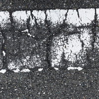 経年劣化で薄くなった路面の白線とひび割れた舗装の写真