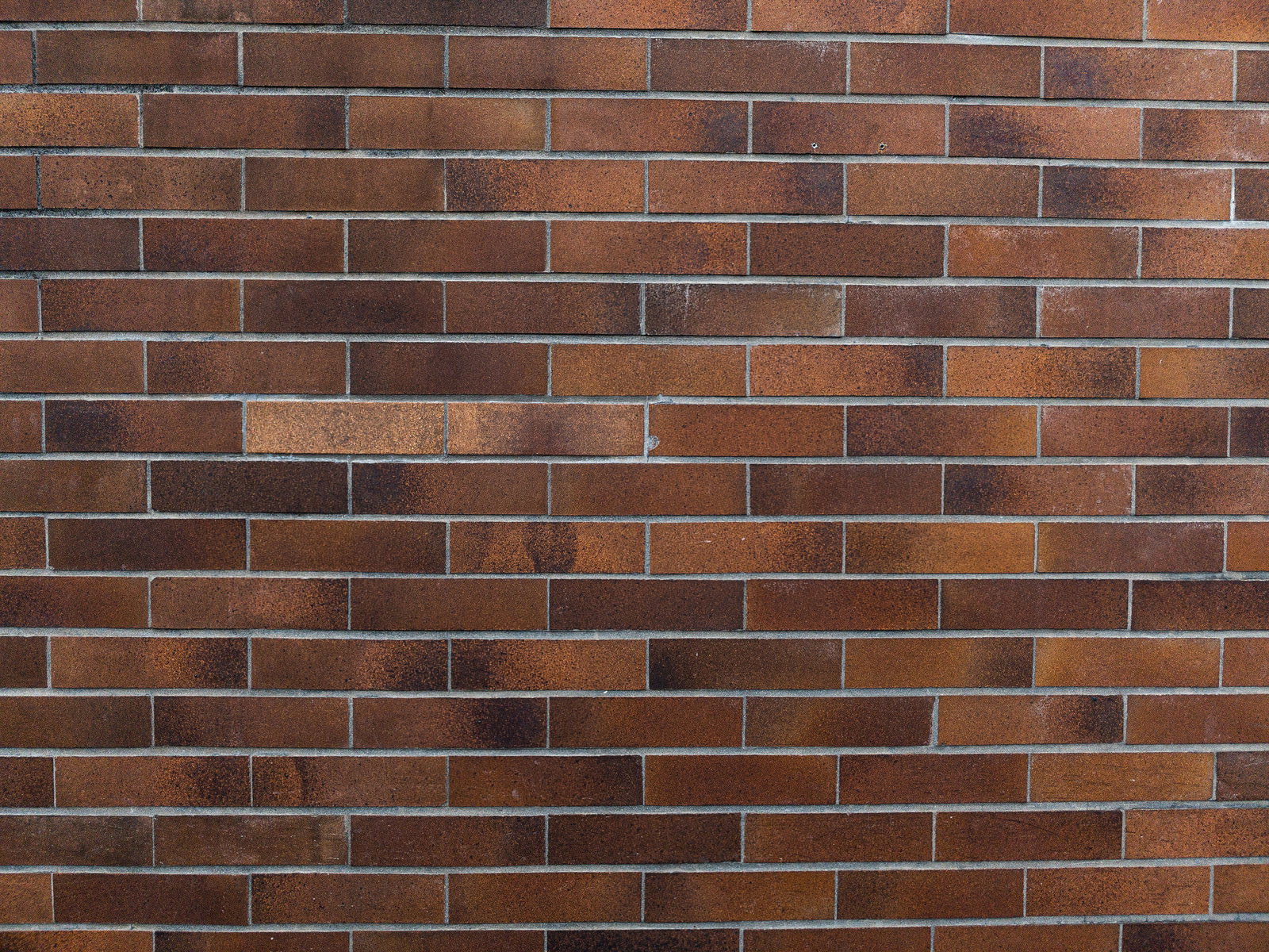 古びた茶色と赤茶色のレンガが規則正しく並んだタイル壁のテクスチャー