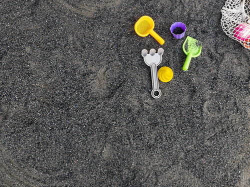 砂場に散らばるカラフルな玩具と砂遊び用具