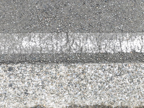 アスファルト路面に薄く残る劣化した白線のテクスチャー