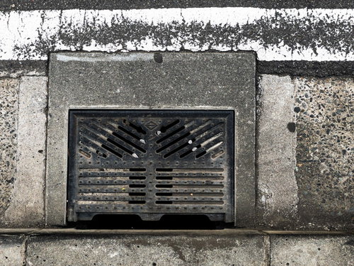 コンクリート道路に設置された側溝の金属製グレート蓋と白線