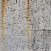 流れ落ちる錆とひび割れた白いモルタル外壁の写真