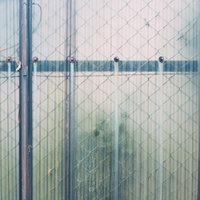 金網フェンス越しに見えるポリカ波板のテクスチャーの写真