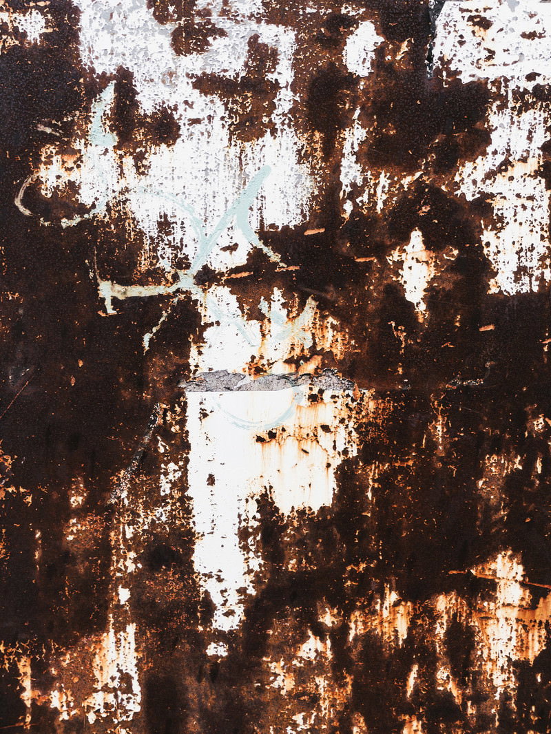 茶色い錆が広がり白い塗装が剥がれた鉄壁の表面