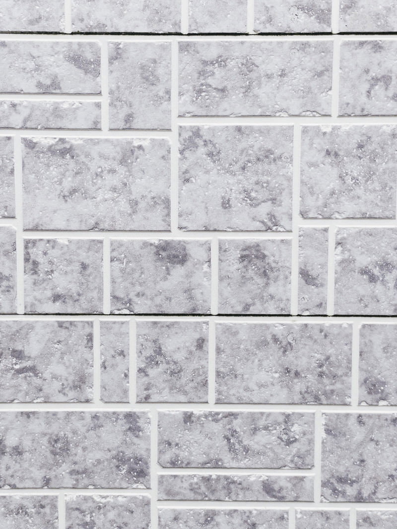 白からグレーの色調のレンガ調タイルが規則的に張られた壁面