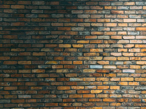 茶色のレンガ壁に右上から当たる照明の光と陰影