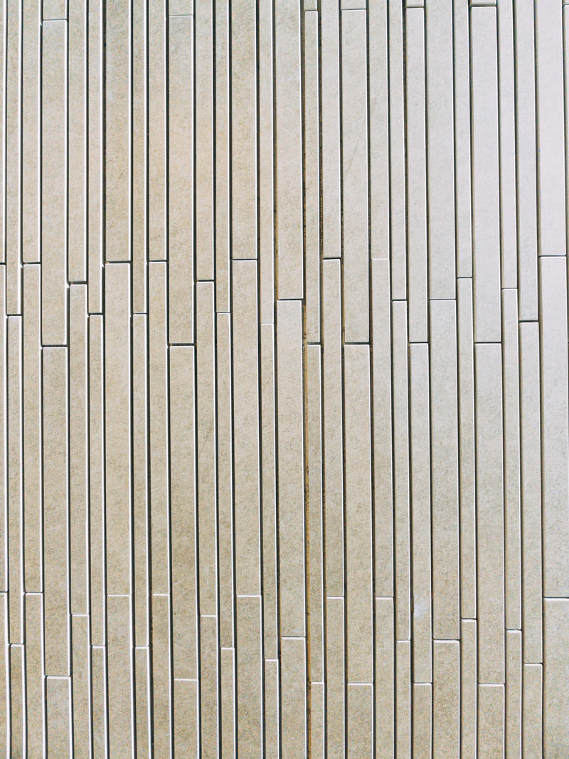 細長いベージュ色のタイルが縦に規則正しく並んだ外壁