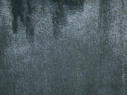 水の染みたグレーのコンクリート擁壁の劣化テクスチャー