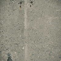 大小の小石が埋まるグレーのコンクリート擁壁のテクスチャーの写真