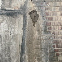 水の染みが目立つコンクリートとレンガの擁壁テクスチャの写真