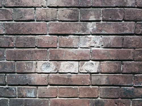 補修跡が見える穴埋めされたレンガ壁のテクスチャ