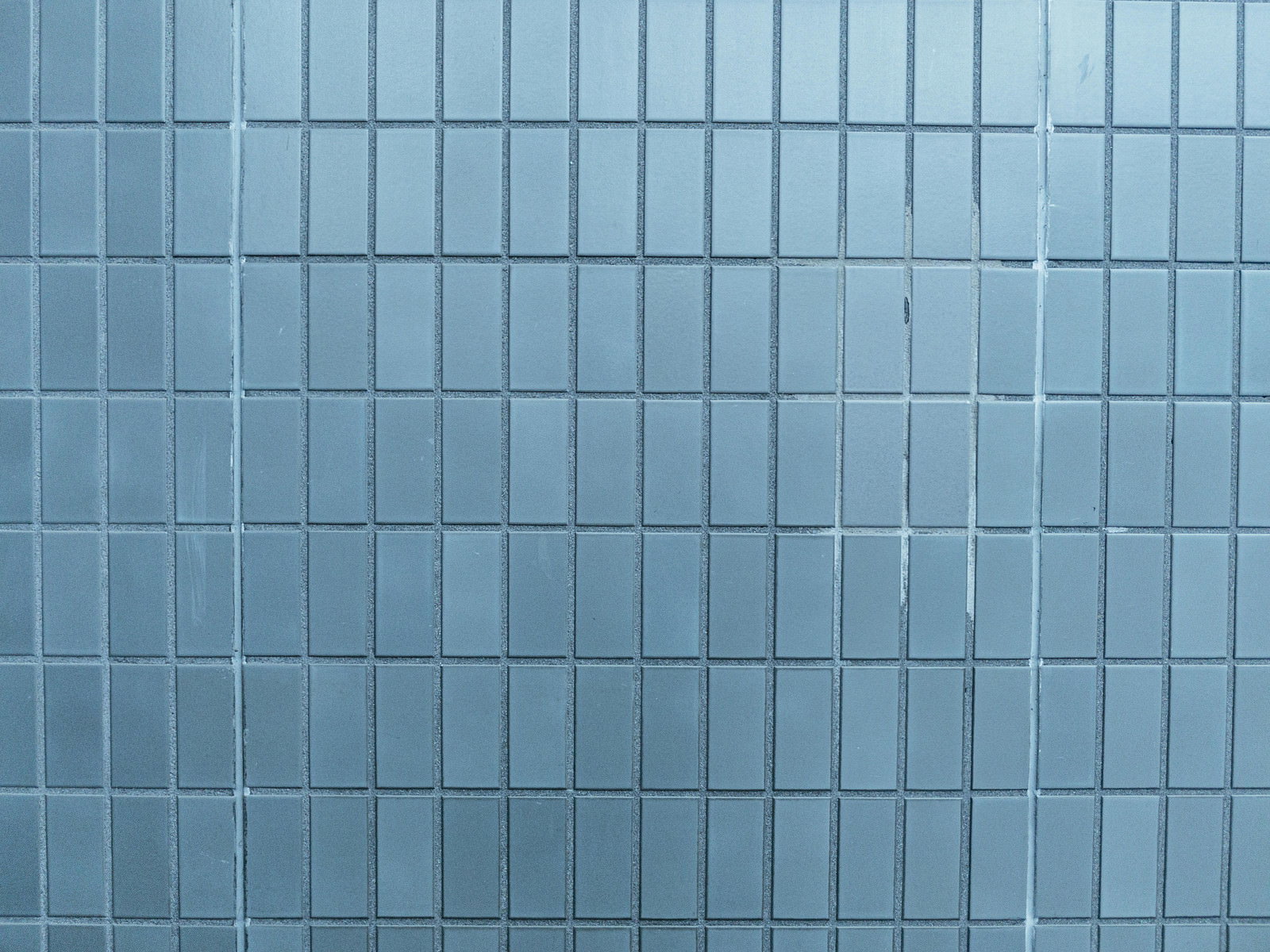 水色のタイルが規則正しく並んだ壁面、明るさにむらがある