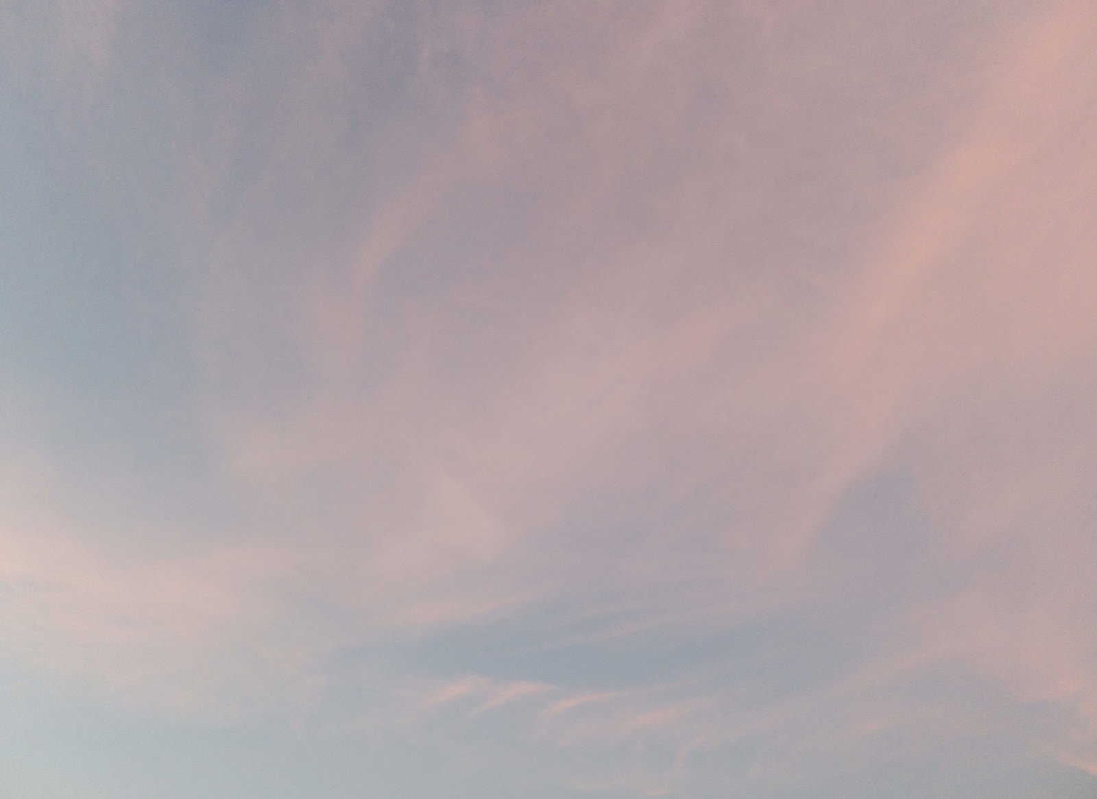 オレンジやピンクの夕焼け空に薄い雲が広がる