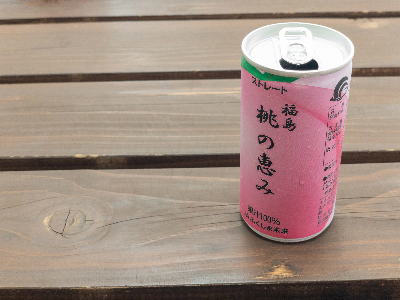 Pink peach nectar canned drink on a wood grain table