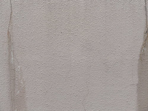 モルタル外壁のクラックから染み出す茶色い汚れのテクスチャー