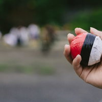 人だかりの中で紅白ボールを握りしめる子どもの手の写真