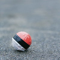 舗装道路にぽつんと置き去られた紅白ボールの写真