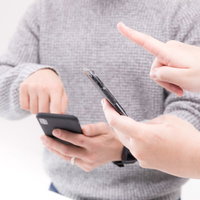 スマホを使って仲間とゲームをするふたりの写真